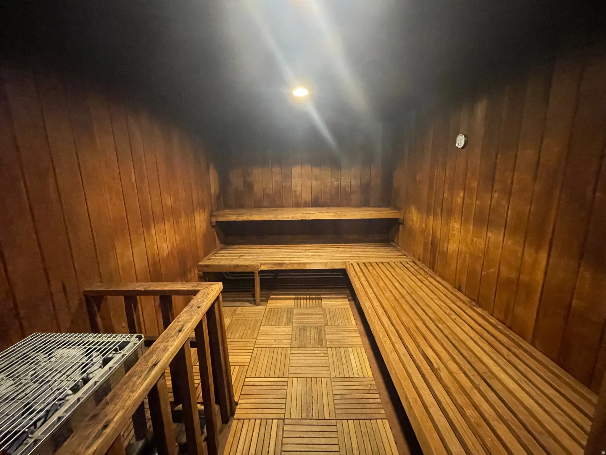 Relaxing sauna with wood walls, enclosed hot rocks and recessed lighting