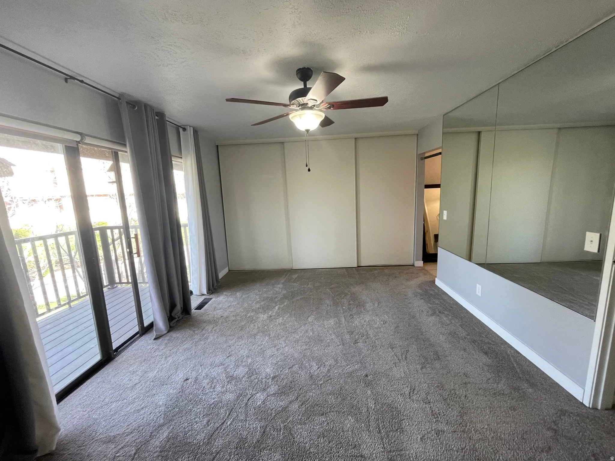 Primary bedroom with carpet floors, triple glass slider to private deck with fabulous views, ceiling fan, double closets, and a textured ceiling
