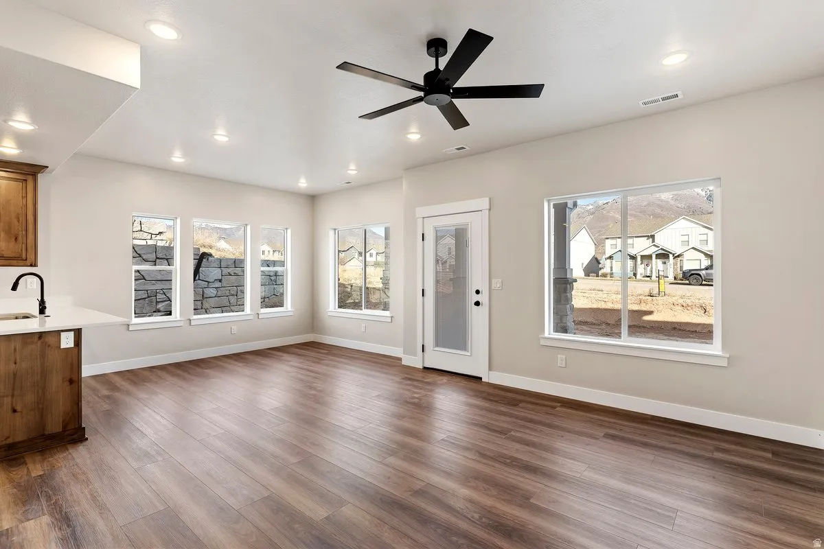 Unfurnished living room featuring dark wood-style flooring, a ceiling fan, and recessed lighting