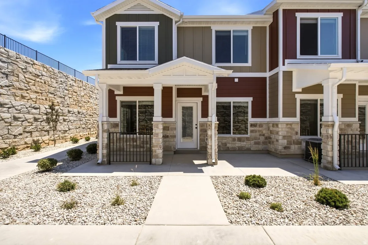 Multi-level exterior featuring a stone retaining wall, varied siding, and white trim accents