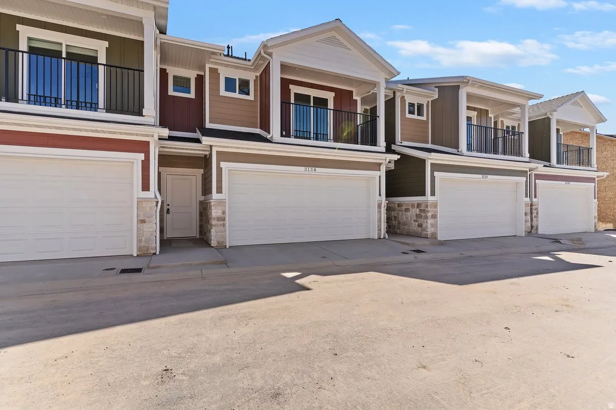 View of front of house featuring a balcony, stone siding, and an attached garage