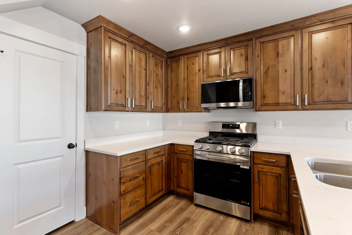 Kitchen featuring stainless steel appliances, wood finish cabinetry, light wood-style flooring, and light stone countertops