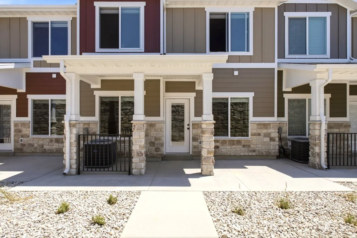 Townhome exterior featuring varied siding colors, stacked stone accents, and white trim