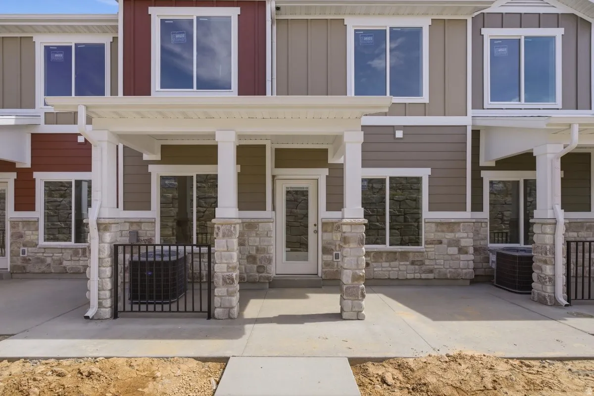 Entrance to property featuring board and batten siding, stone siding, and covered porch