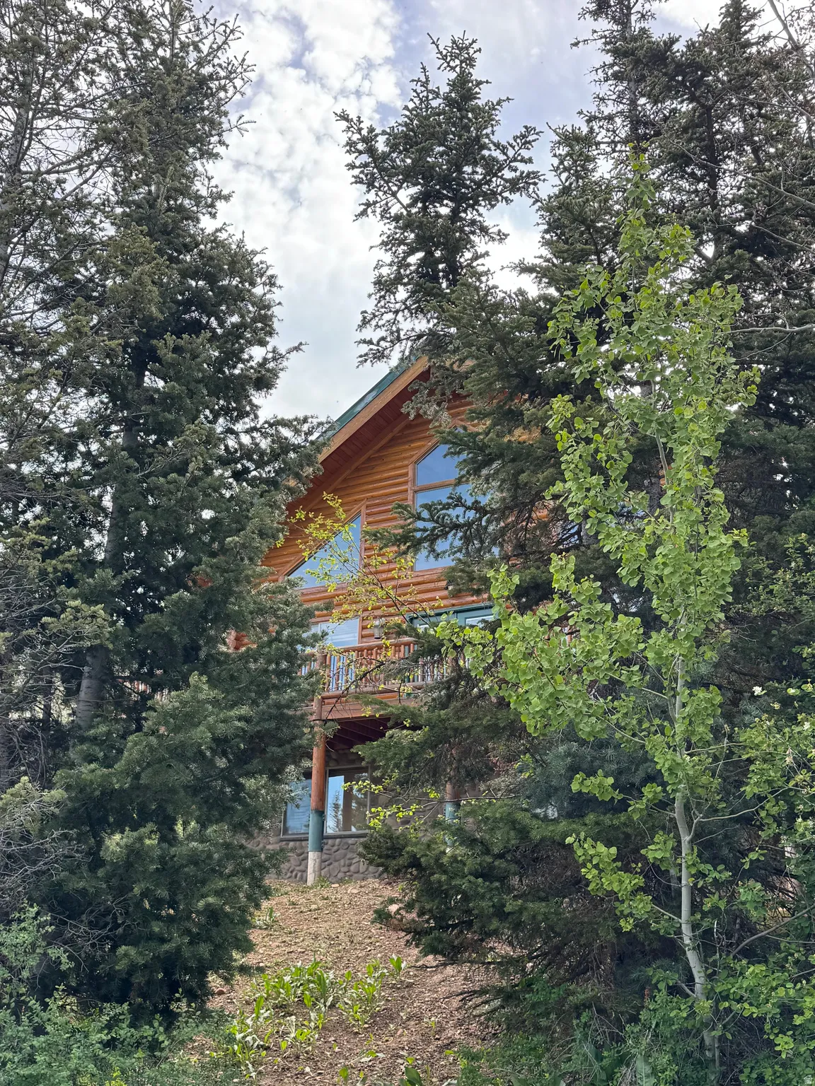 Log cabin exterior featuring a prominent gabled roofline and natural wood siding