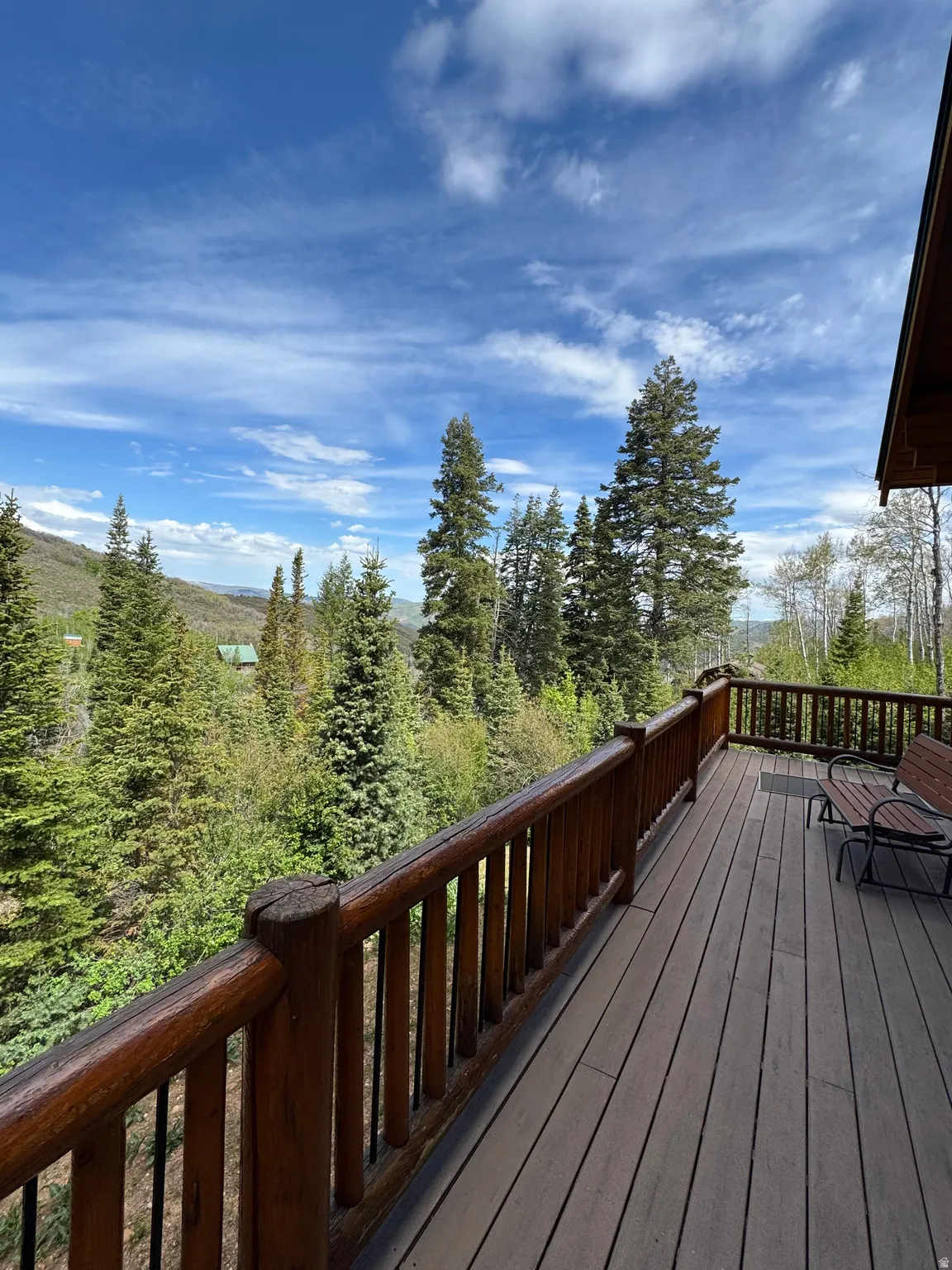 Spacious outdoor deck featuring wood-finish decking and rustic log railing