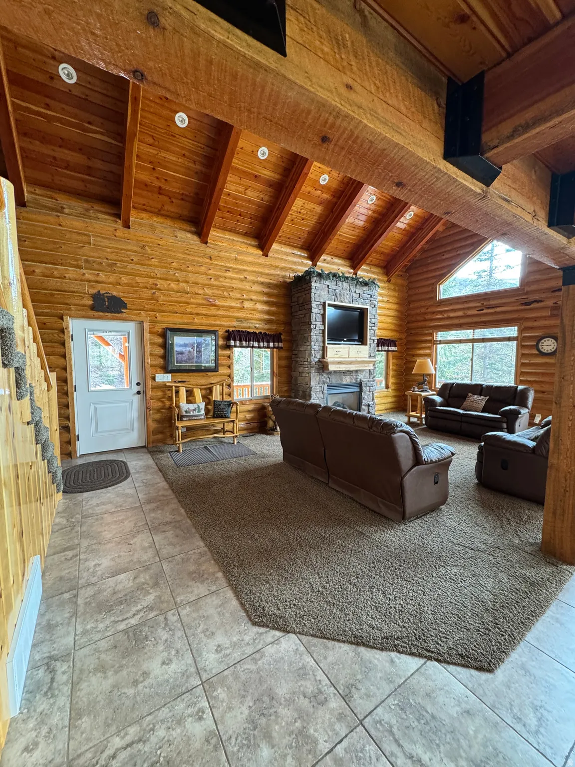Living area featuring rustic walls, a high wooden beamed ceiling, a fireplace, and plenty of natural light