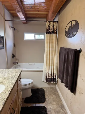 Bathroom with vanity, shower / bath combo, and a wood ceiling with exposed beams