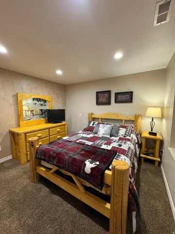Bedroom featuring dark carpet, recessed lighting, and an accent wall