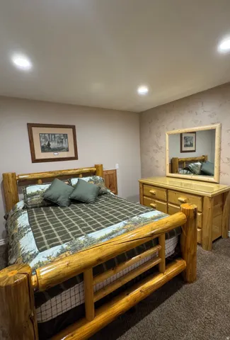 Bedroom featuring dark carpet, recessed lighting, and wallpapered walls
