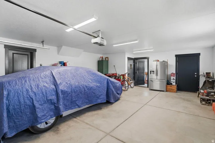 Garage with stainless steel fridge with ice dispenser and a garage door opener