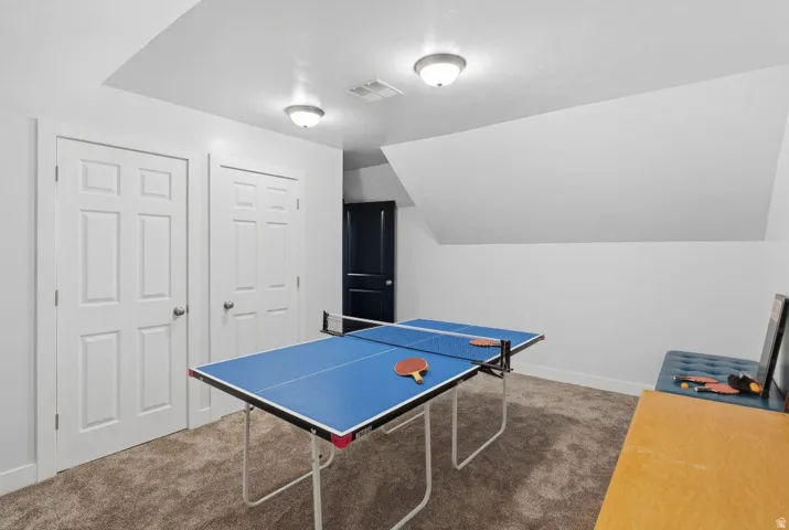 Rec room with carpet floors and vaulted ceiling