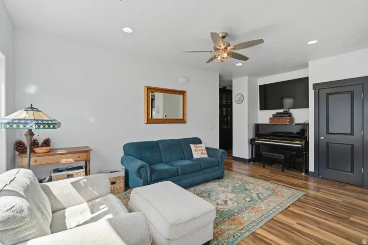 Living area with wood finished floors, a ceiling fan, and recessed lighting