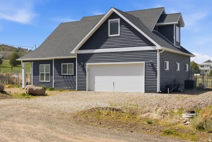 View of front of home featuring a garage, driveway, and a shingled roof
