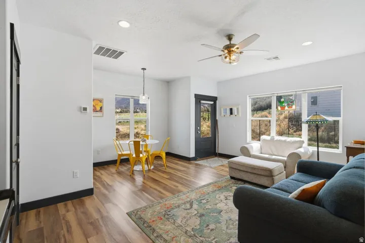 Living room featuring dark wood-type flooring, a ceiling fan, and recessed lighting