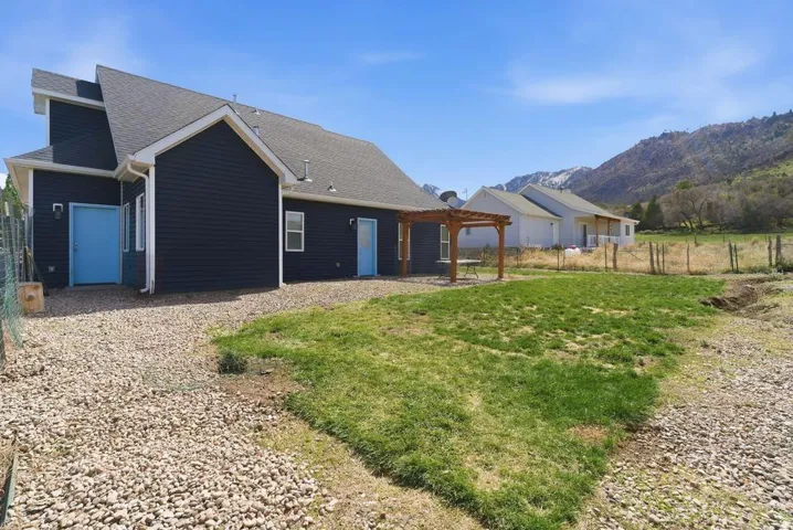 Back of property featuring a shingled roof, a pergola, and a mountain view