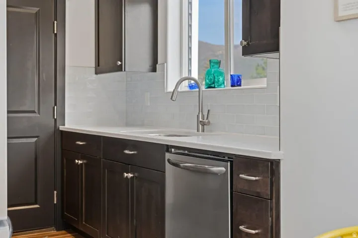 Kitchen with dark wood finish cabinets, dishwasher, and light stone counters