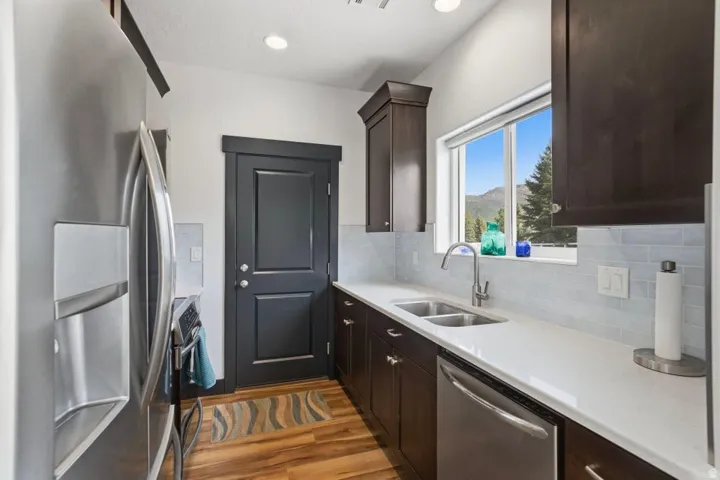Kitchen featuring stainless steel appliances, dark wood finish cabinets, decorative backsplash, and recessed lighting