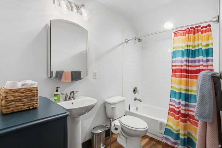 Full bathroom featuring shower / tub combo with curtain and dark wood-type flooring