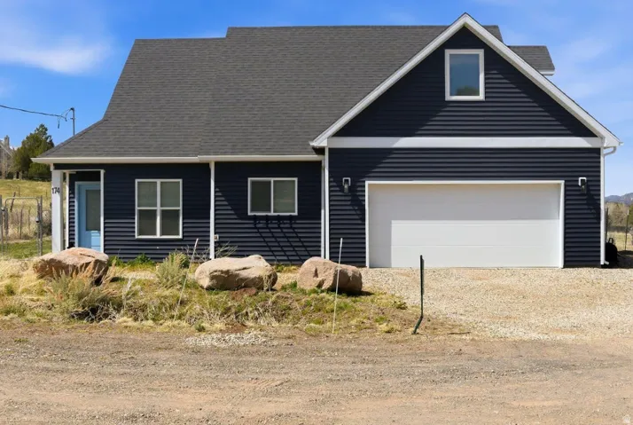 View of front of property featuring dirt driveway and a garage