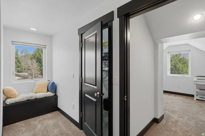 Corridor featuring light colored carpet, plenty of natural light, and recessed lighting