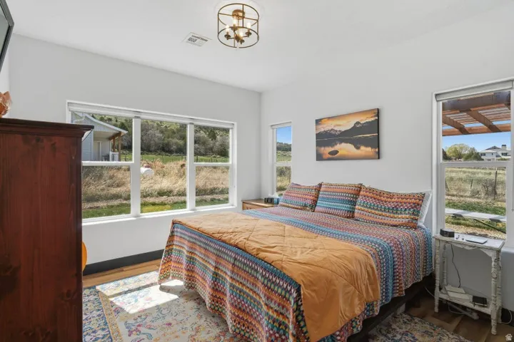 Bedroom with wood finished floors, multiple windows, and hanging lights