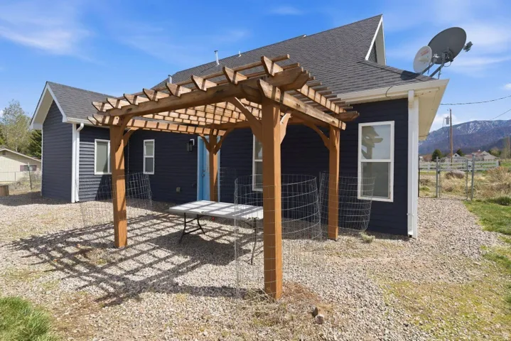 Back of property with a pergola, roof with shingles, and a patio area
