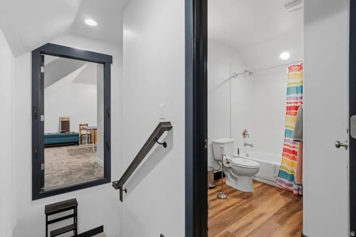 Full bath with light wood-style floors, shower / tub combo with curtain, vaulted ceiling, and recessed lighting