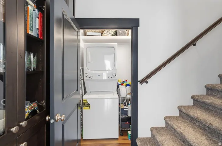 Laundry area with stacked washer / dryer and light wood finished floors