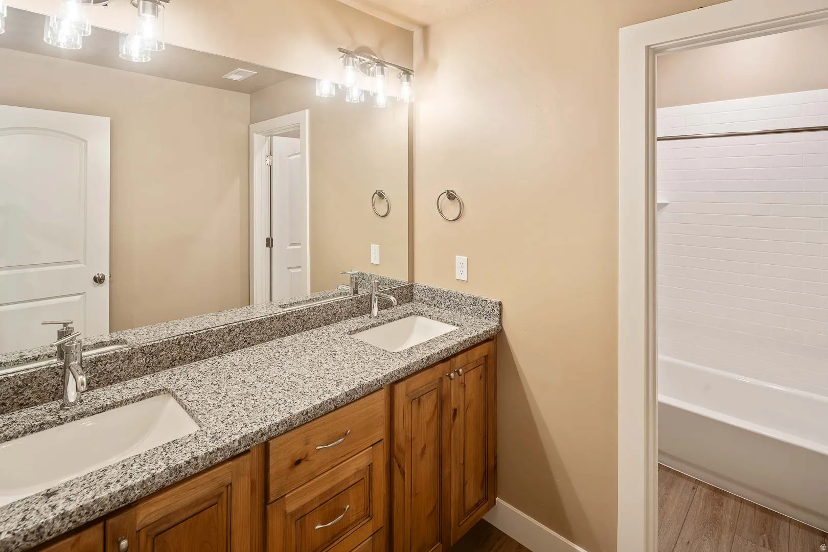 Full bath featuring double vanity, wood finished floors, and bathtub / shower combination