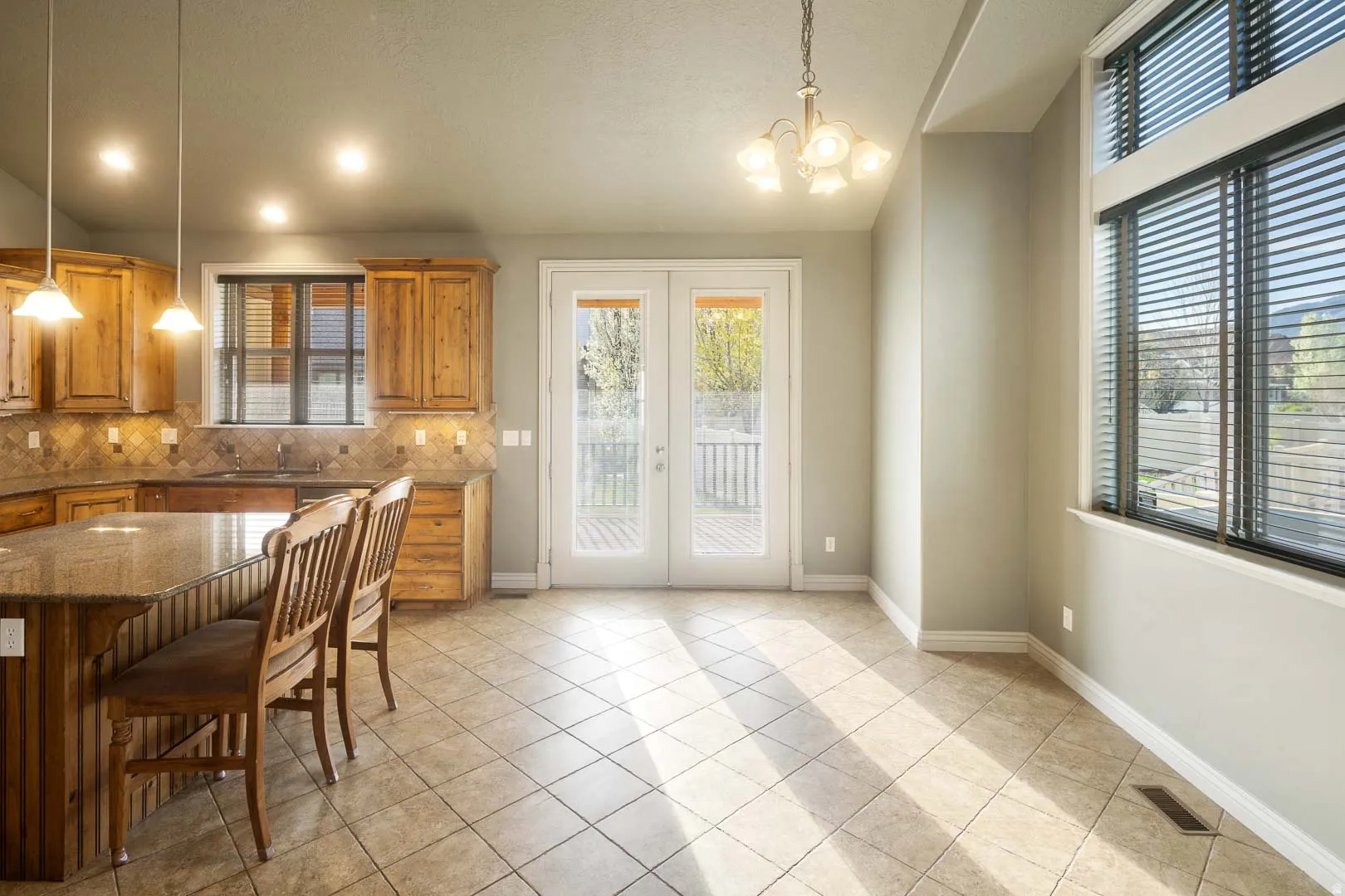 Kitchen featuring french doors, dark stone countertops, wood finish cabinets, hanging lights, and vaulted ceiling