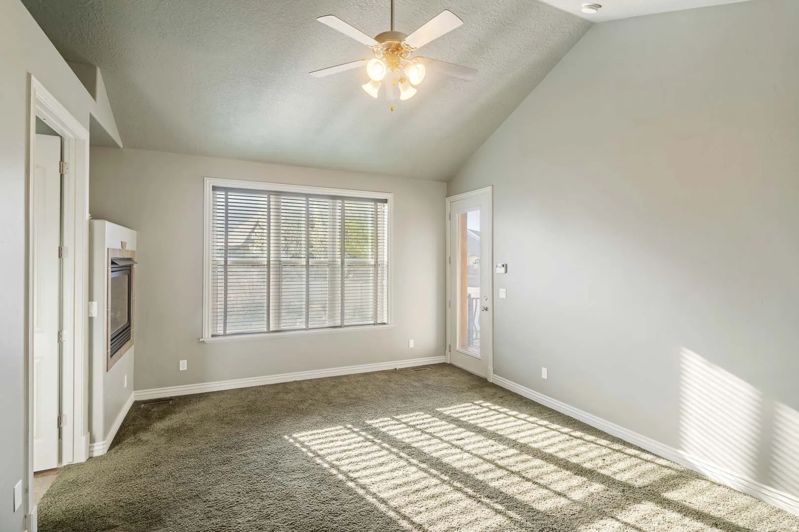 Empty room with a ceiling fan and light carpet
