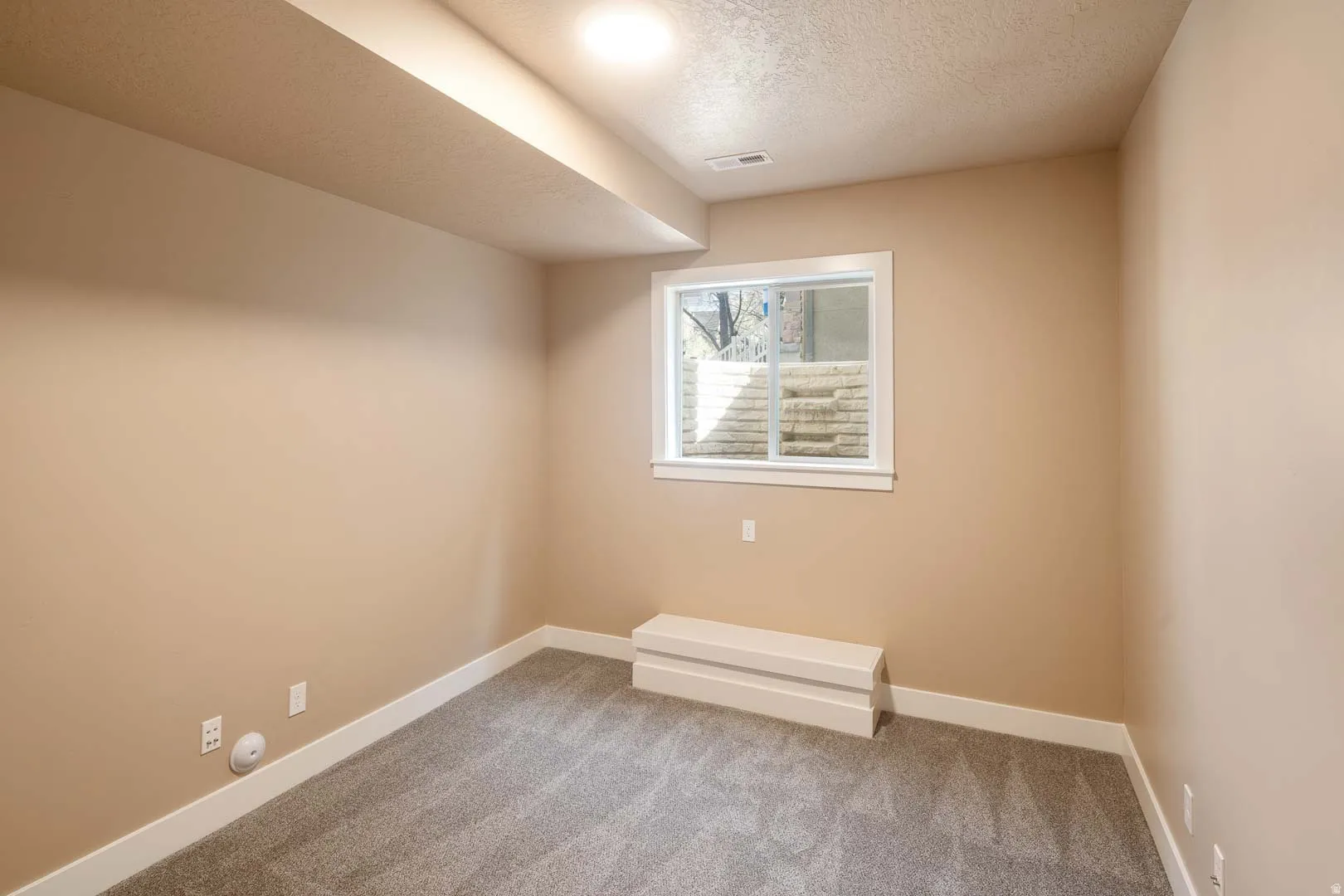 Empty room with a textured ceiling and light carpet
