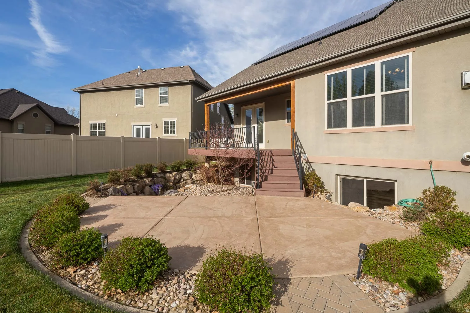 Rear view of house featuring roof mounted solar panels, stucco siding, roof with shingles, and a porch