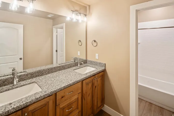 Full bath featuring double vanity, wood finished floors, and bathtub / shower combination