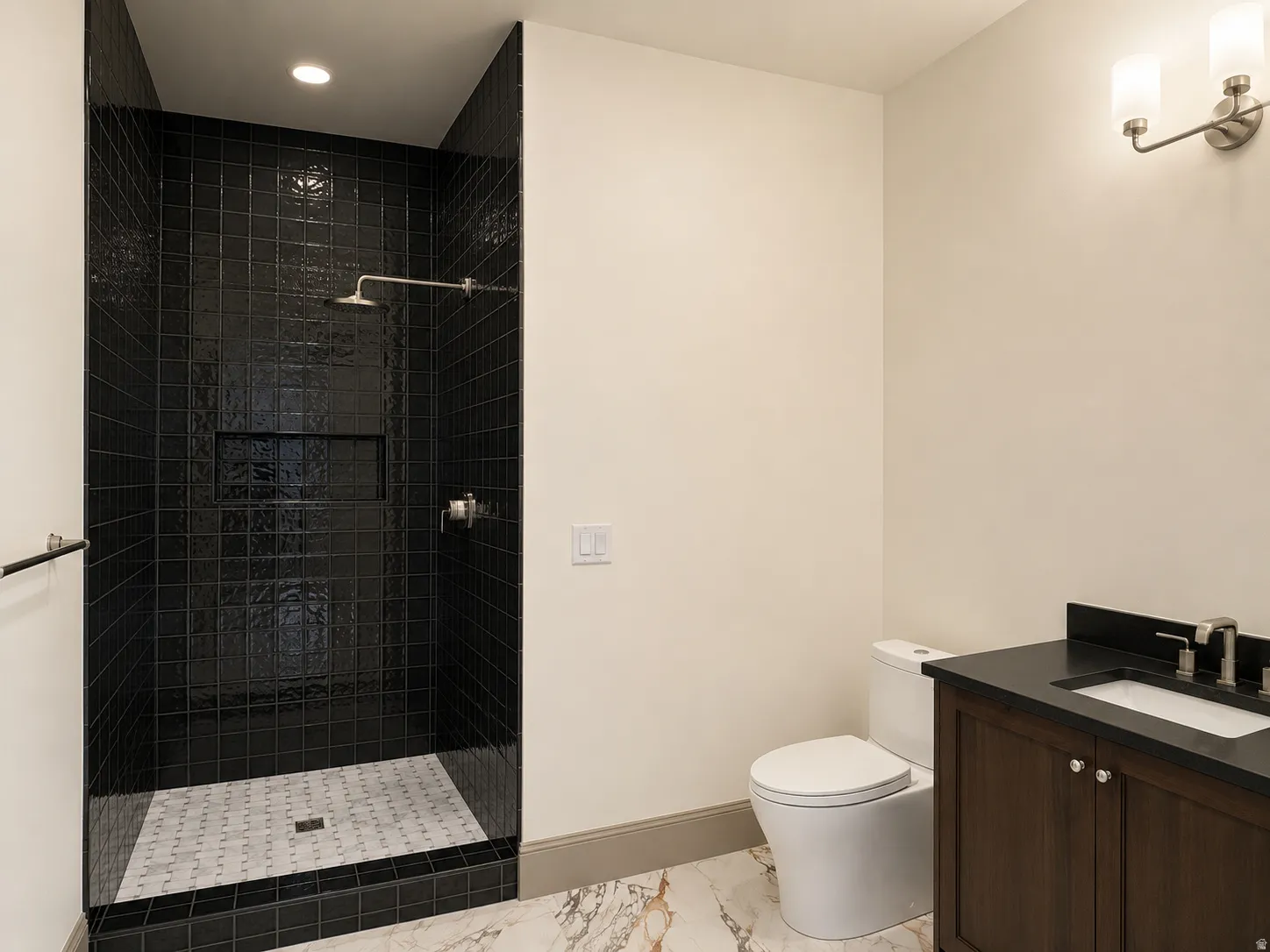 Walk-in shower with dark tile surround and recessed niche, rainfall showerhead, and patterned tile floor