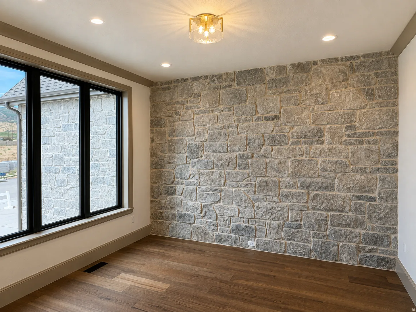 Stone accent wall, recessed lighting, wood-finish flooring, and a contemporary flush mount fixture
