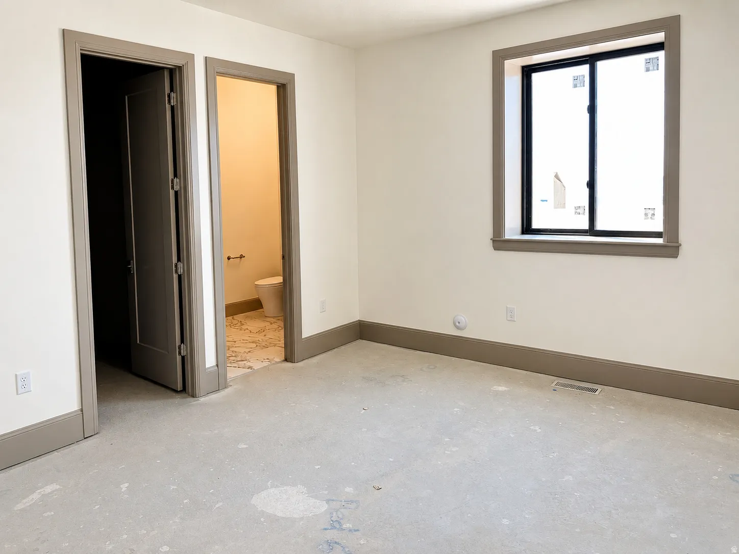 Room with light-toned walls, contrasting gray trim, and a window featuring dark framing