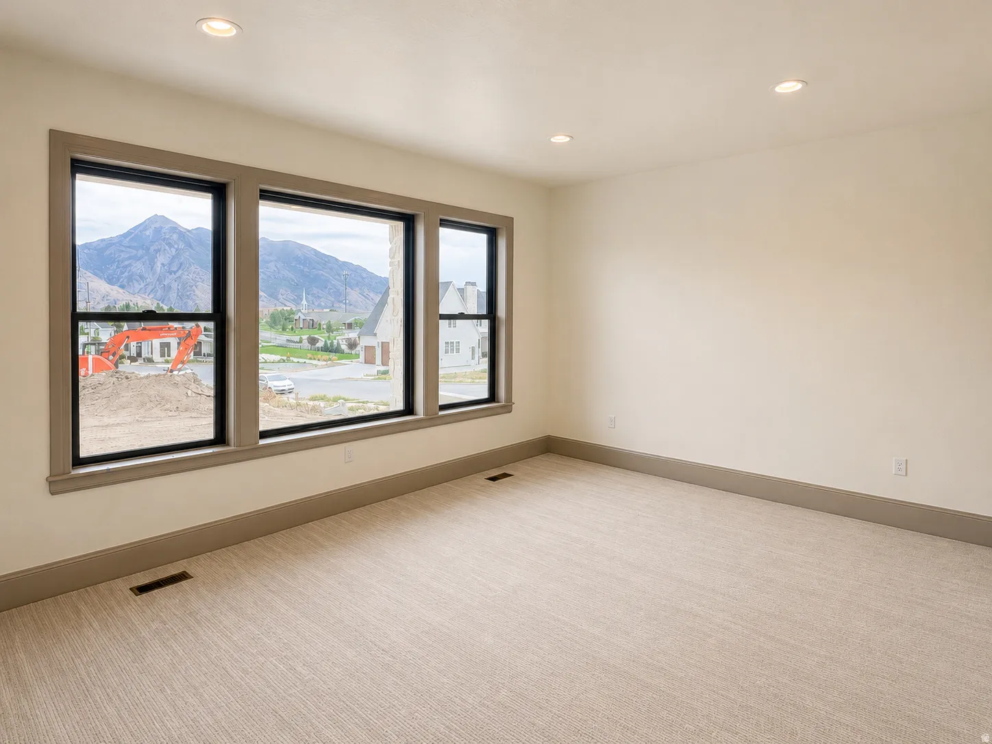 Recessed lighting, light-toned walls, and neutral carpeting