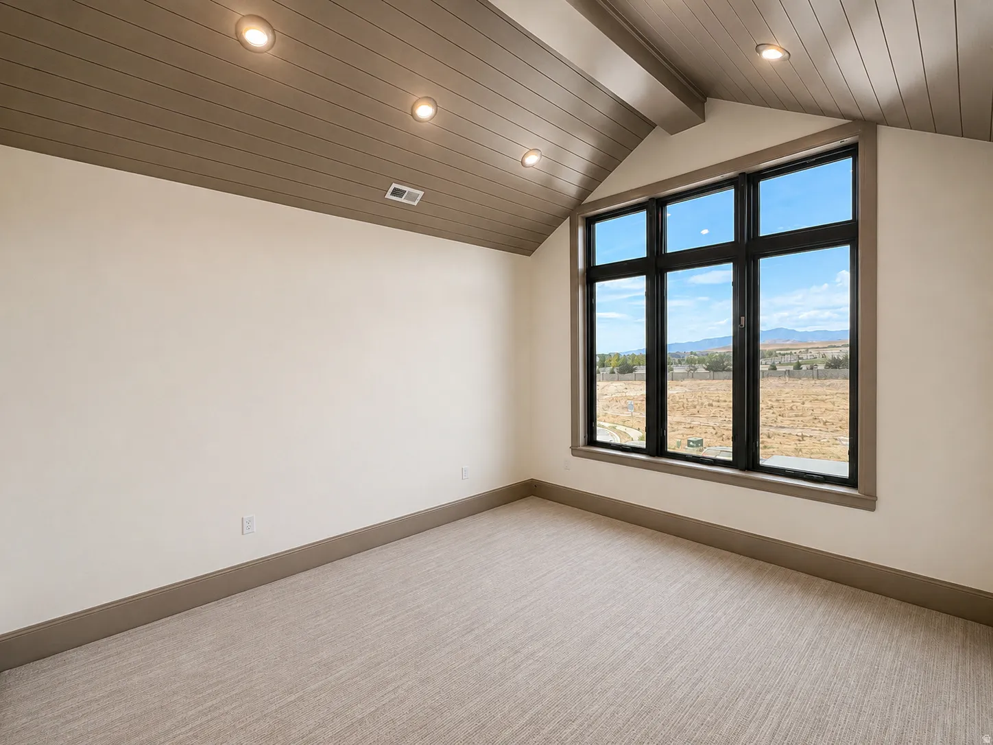 Vaulted ceiling with wood-finish planks, recessed lighting, and a large multi-pane window