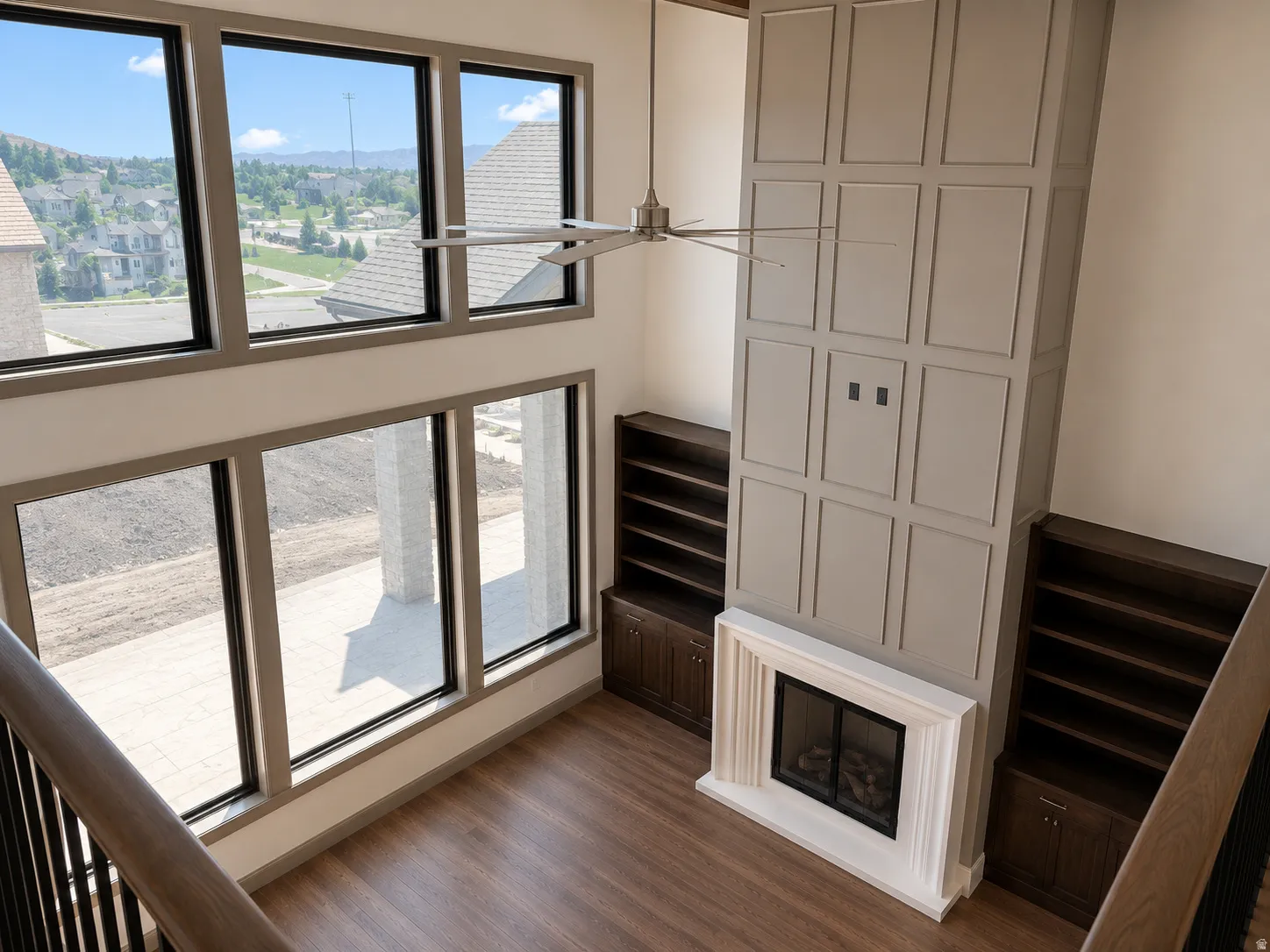 Two-story living area featuring a built-in fireplace with a paneled surround, integrated shelving, and wood-finish flooring