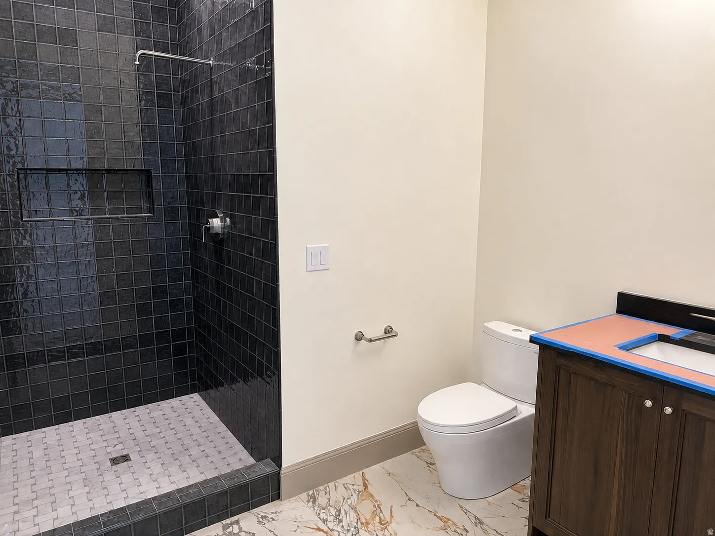 Walk-in shower with black subway tile surround and mosaic tile floor
