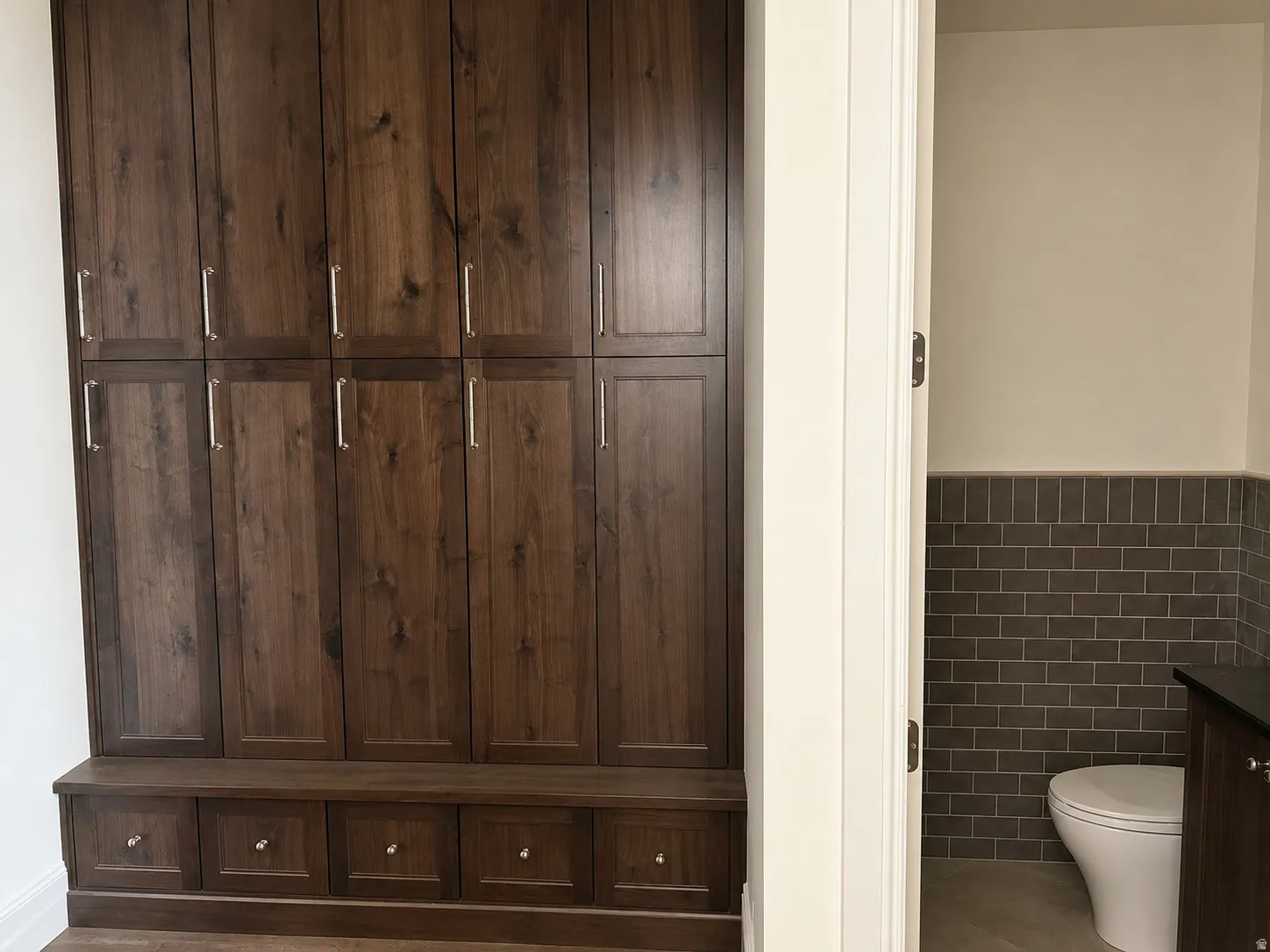 Integrated wood-finish cabinetry with silver-tone hardware and built-in bench seating. Half bath with cabinet vanity.
