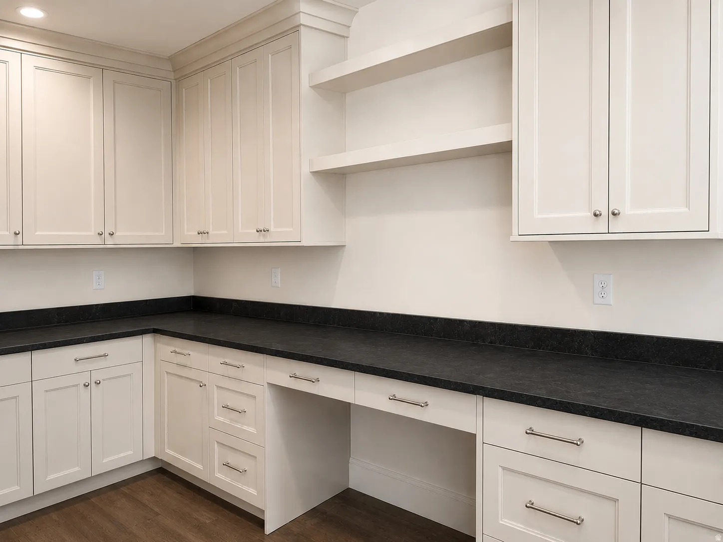 Built-in cabinetry featuring cream-colored shaker-style doors and drawers, dark countertops, a dedicated desk area, and open shelving