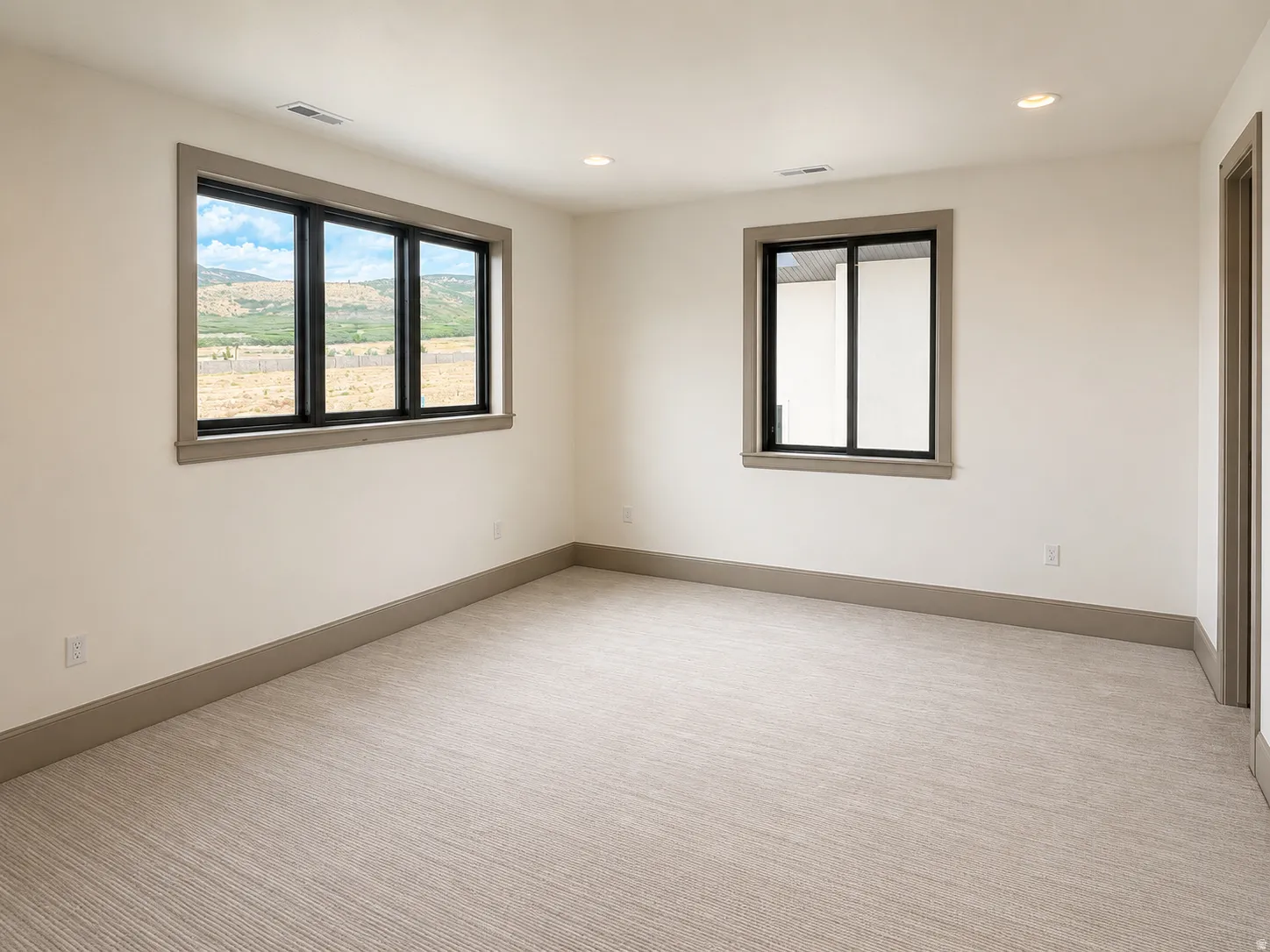 Carpeted room with recessed lighting, two windows with black frames, and light-colored wall paint
