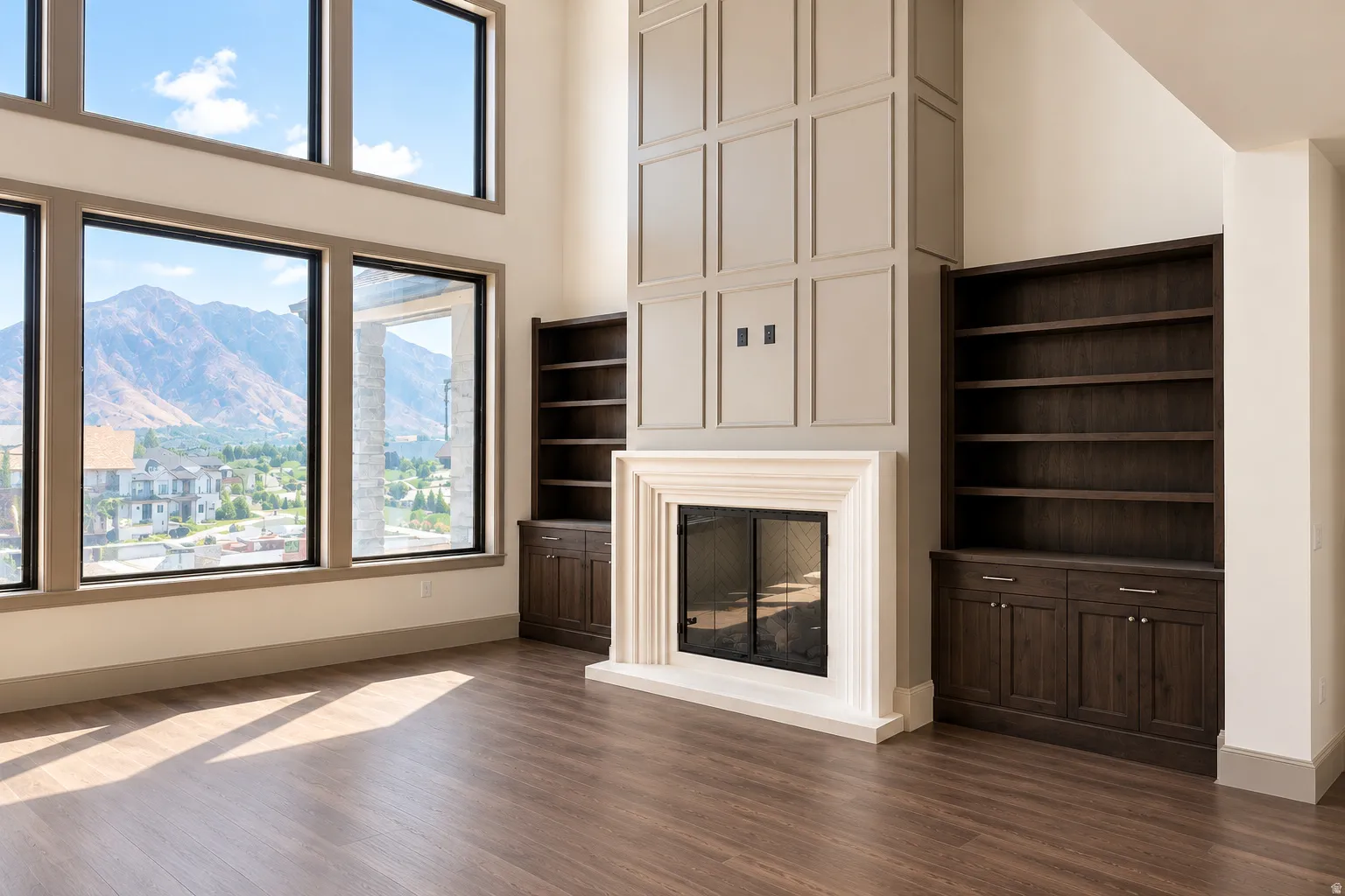 Spacious room featuring large windows, a prominent fireplace with a carved stone mantel, and built-in wood cabinetry with shelving