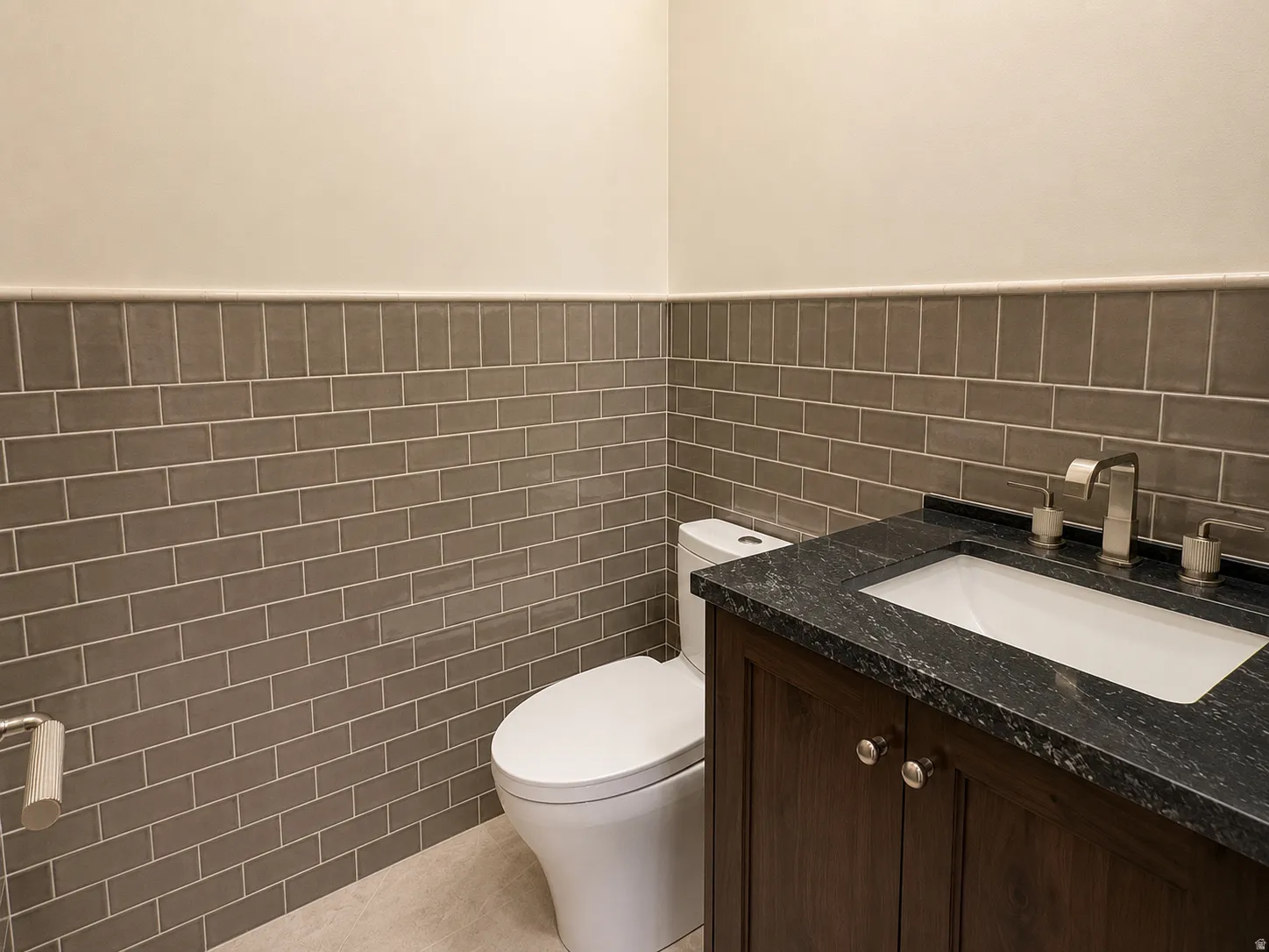 Dark wood-finish vanity with an undermount sink, dark stone countertop, and a brushed nickel faucet