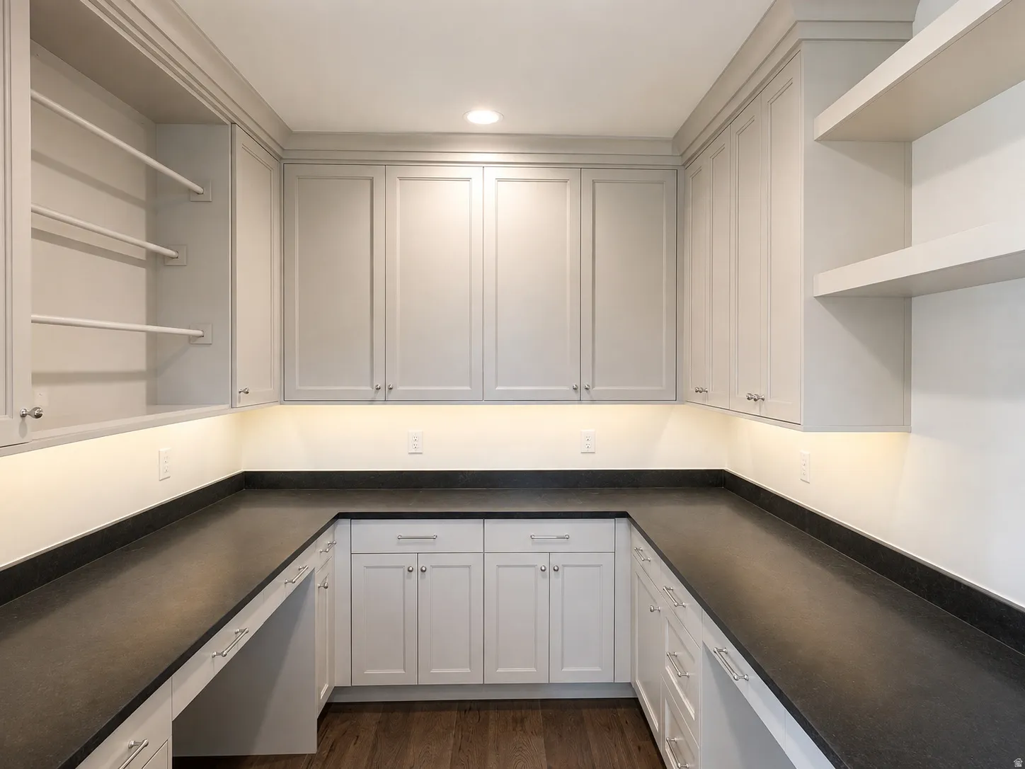 Extensive U-shaped dark stone-finish countertops with light gray cabinetry
