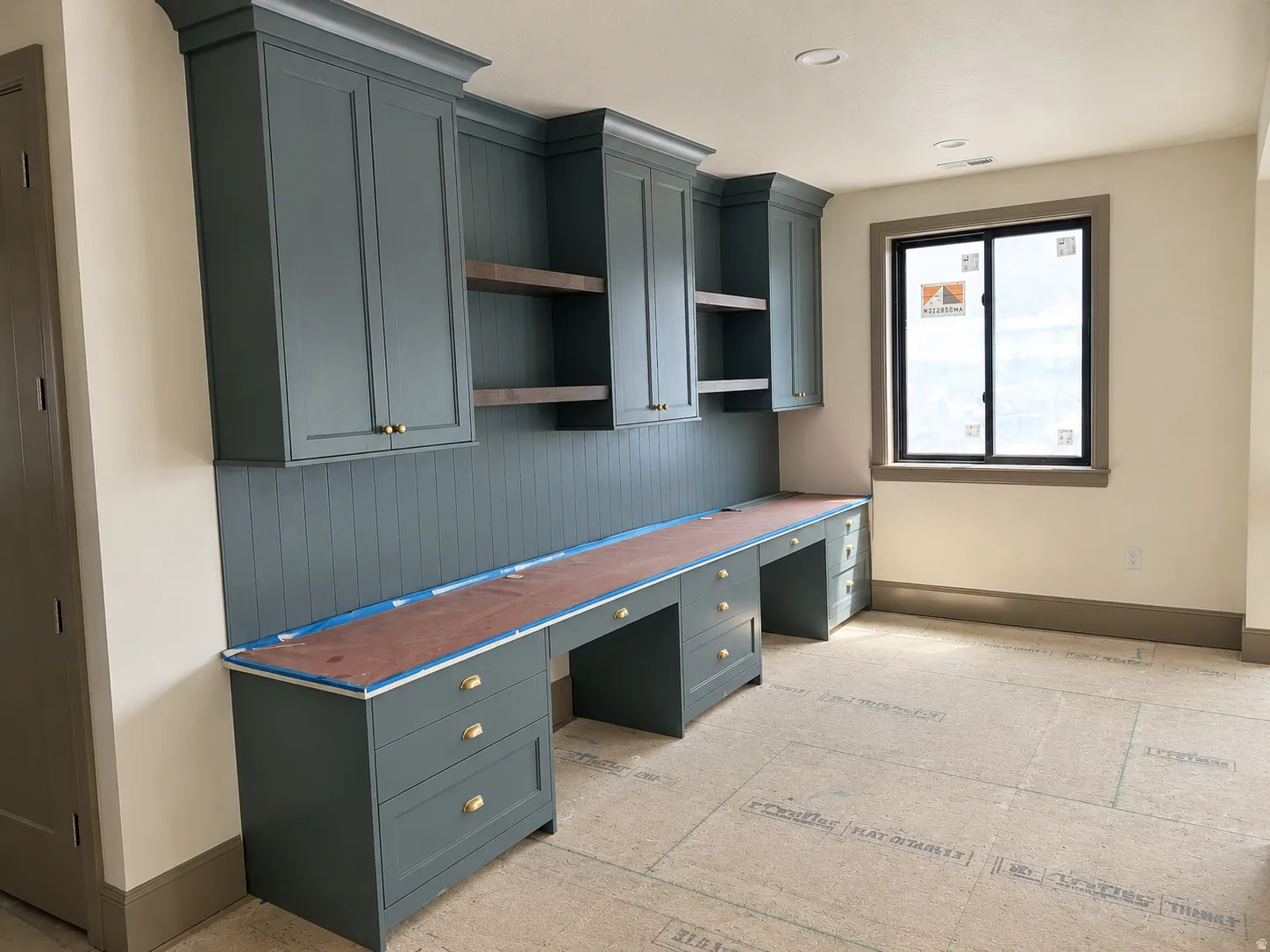 2nd Floor Loft with built-in cabinetry in a deep blue finish featuring brass hardware, wood-finish shelving, and a beadboard backsplash