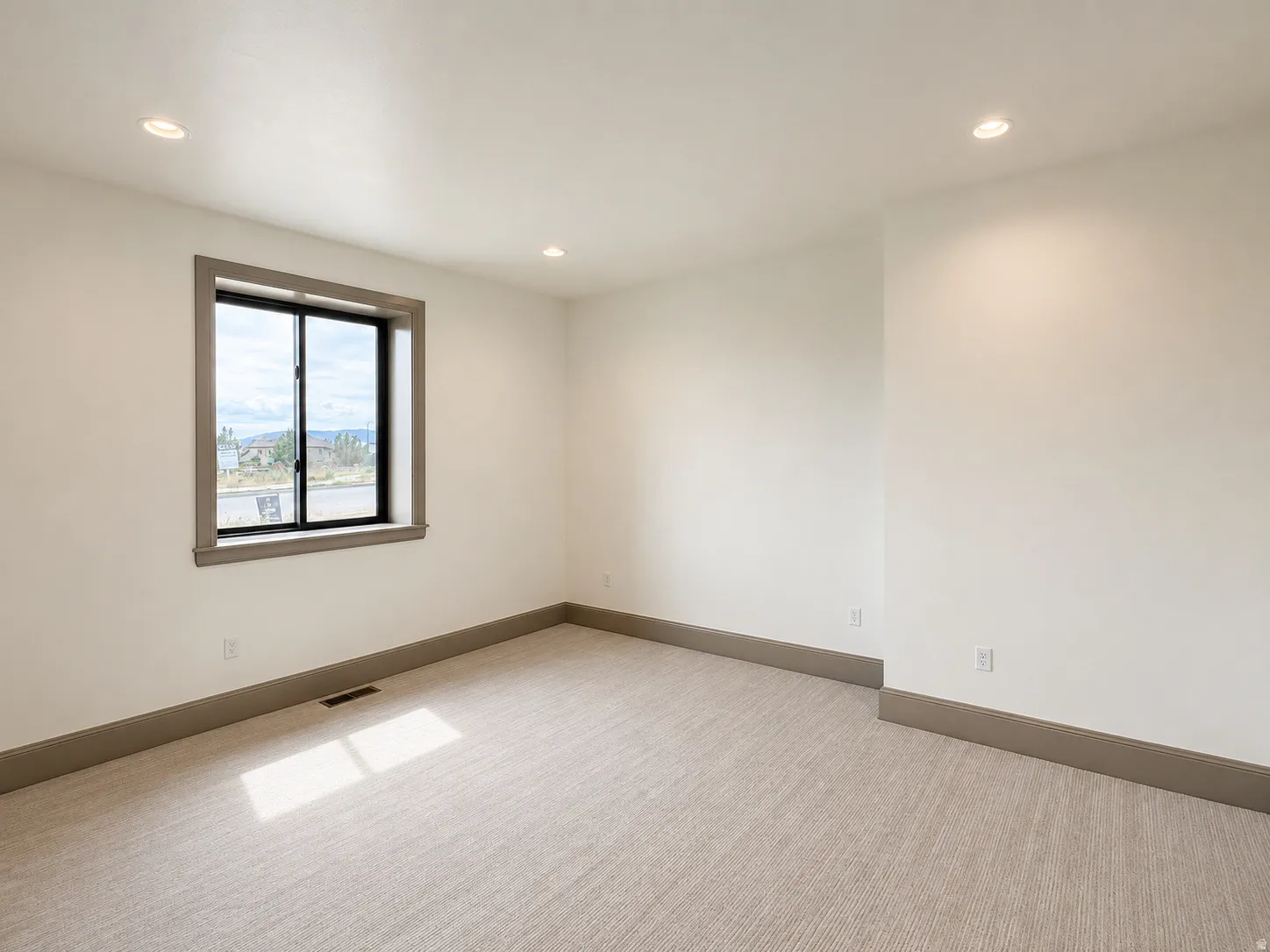 Recessed lighting, neutral-toned walls, and a large window with contrasting trim